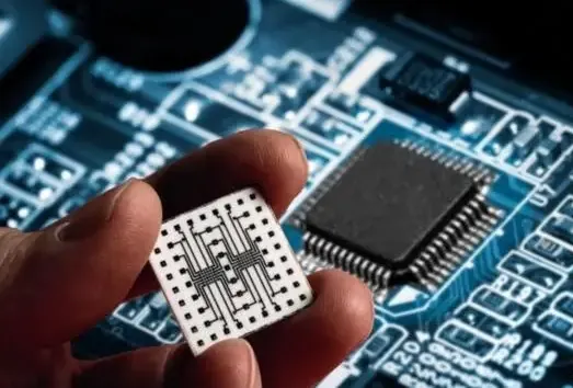 Close-up of an electronic component held above a circuit board